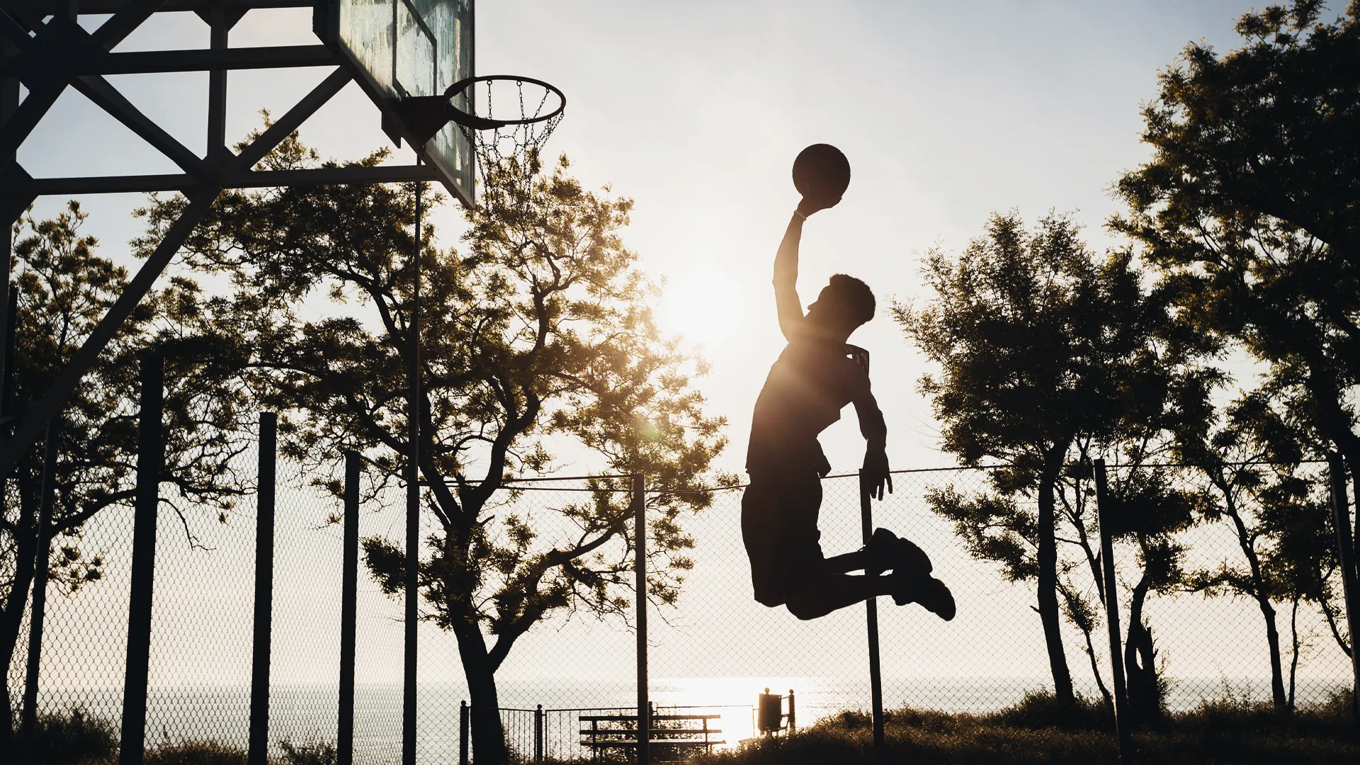 Jugador de básquetbol saltando al atardecer