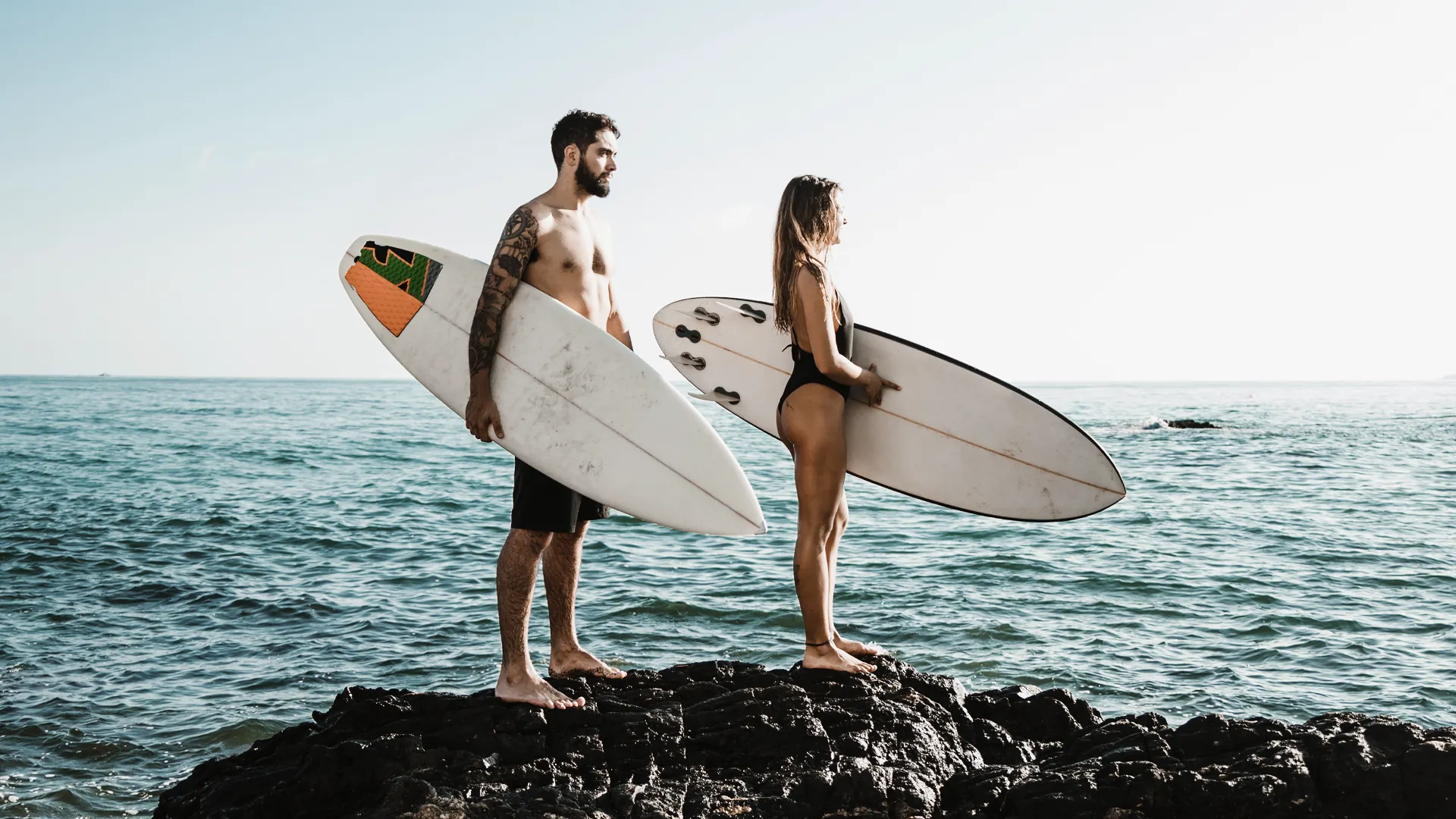 Pareja de surfistas junto a la costa